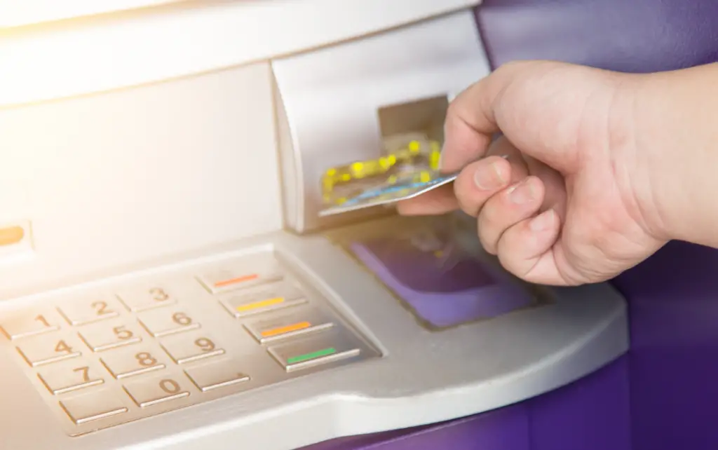hand inserting ATM credit card into bank machine
